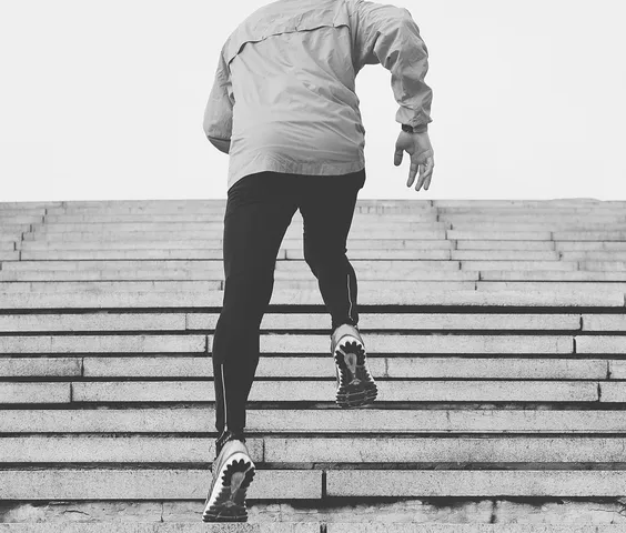 Black-and-white photograph of a person running up outdoor stairs