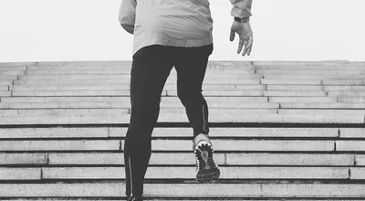 Black-and-white photograph of a person running up outdoor stairs